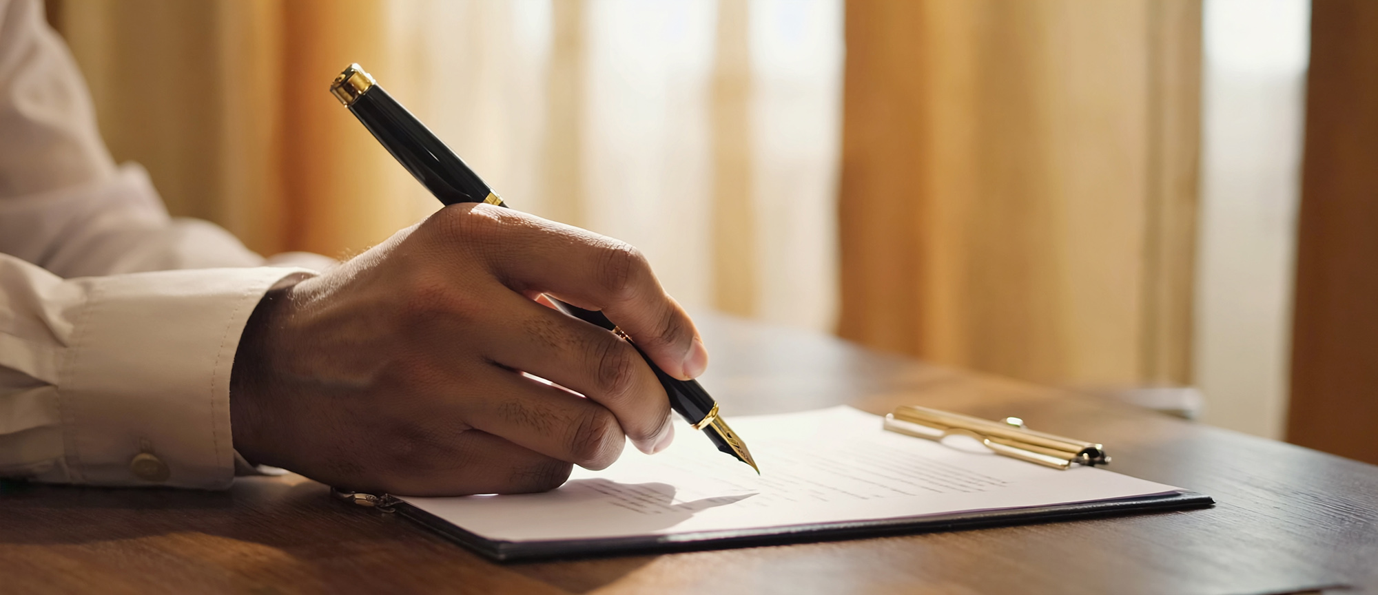man’s hand writing on paper at desk symbolizing recovery routine and accountability